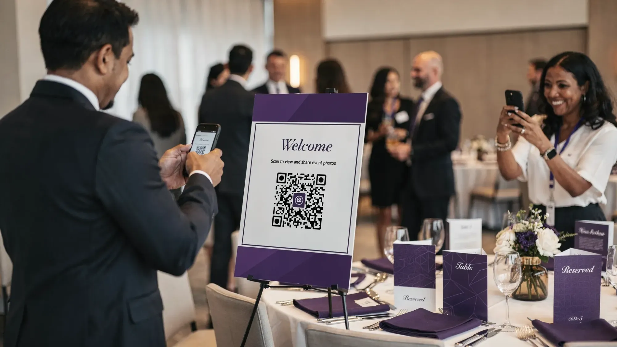 An event setup with tasteful table tents and a welcome sign that includes a QR code for a shared event photo gallery. Guests are mingling nearby, and one guest is scanning the QR code with a phone while another takes a candid photo.