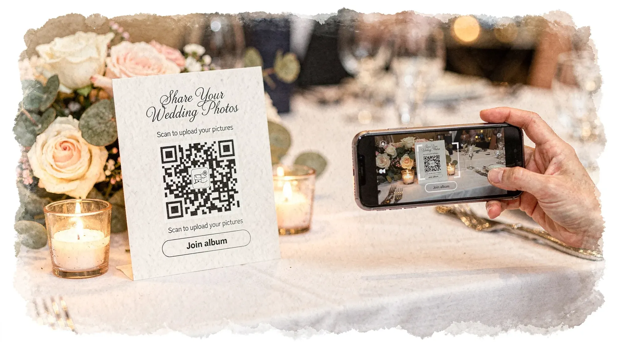 A wedding reception table tent with a QR code for sharing photos, placed next to candles and floral decor, while a guest holds a phone over the code ready to scan. The phone screen faces the QR code and shows a camera-style join flow.