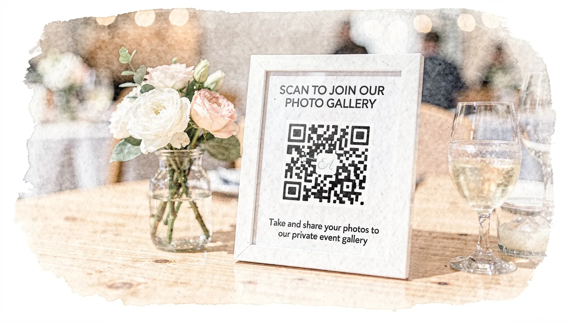 A tabletop QR code sign at an event, placed next to a centerpiece and drinks, with simple text inviting guests to scan to take and share photos to a private event gallery.